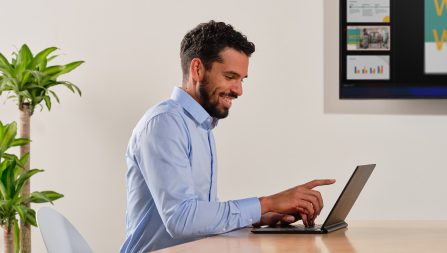 Man sitting at table using touchscreen on laptop