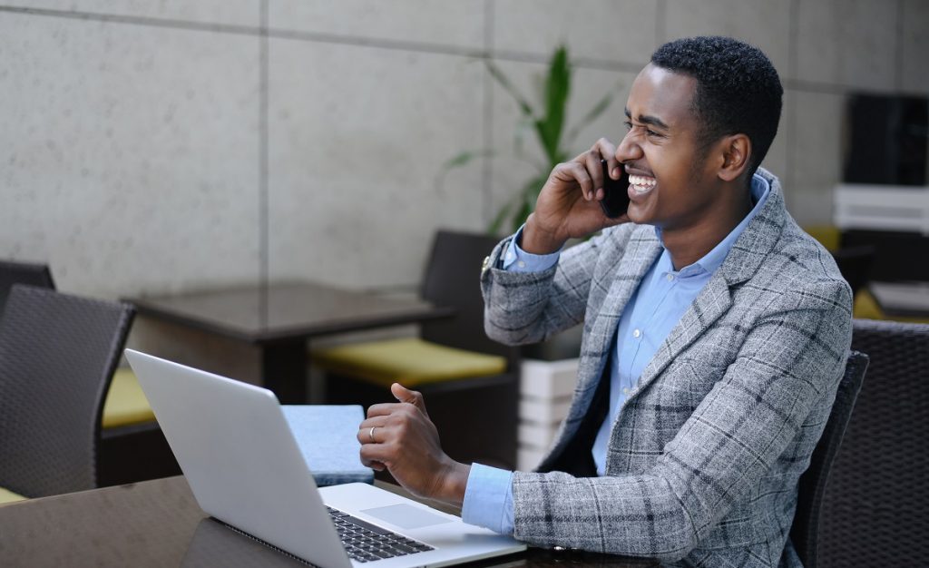 Businessman sitting as desk with laptop while talking on the phone
