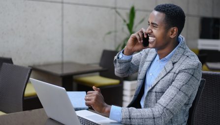 Businessman sitting as desk with laptop while talking on the phone
