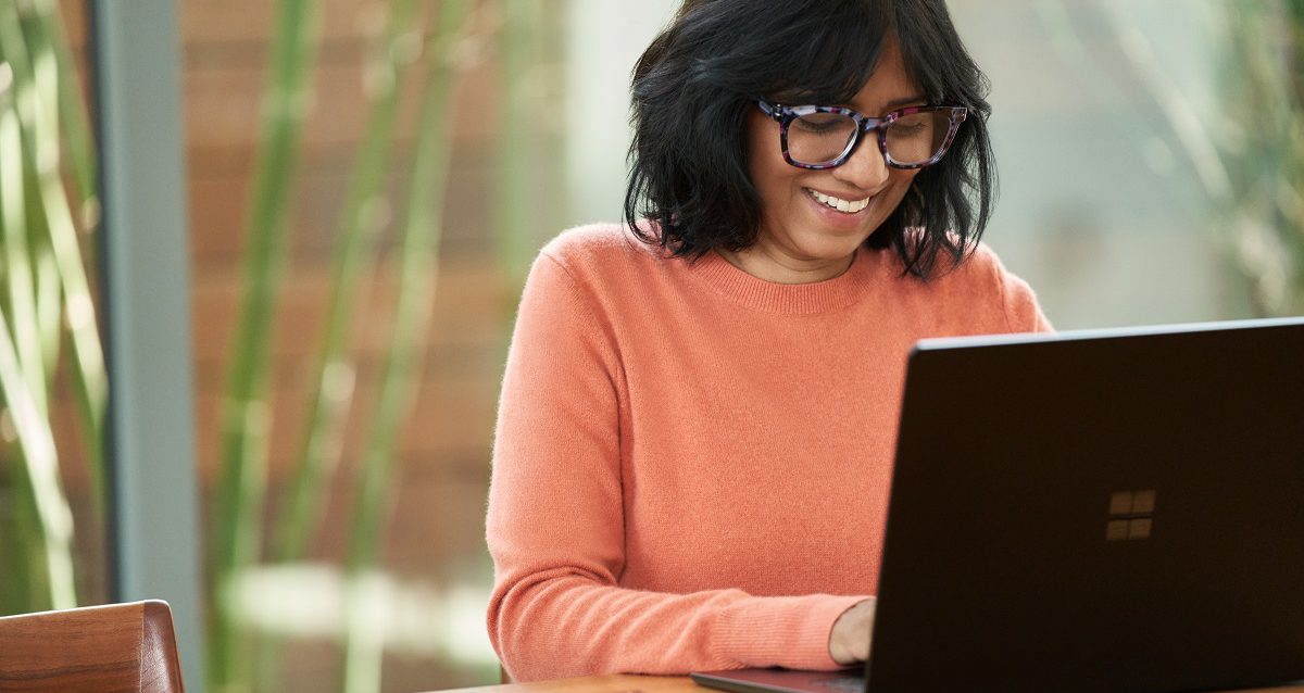 Smiling woman typing on Windows laptop
