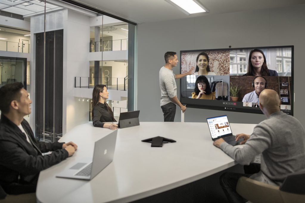 four people conference calling with others on large screen