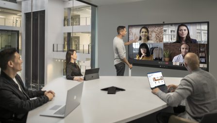 four people conference calling with others on large screen