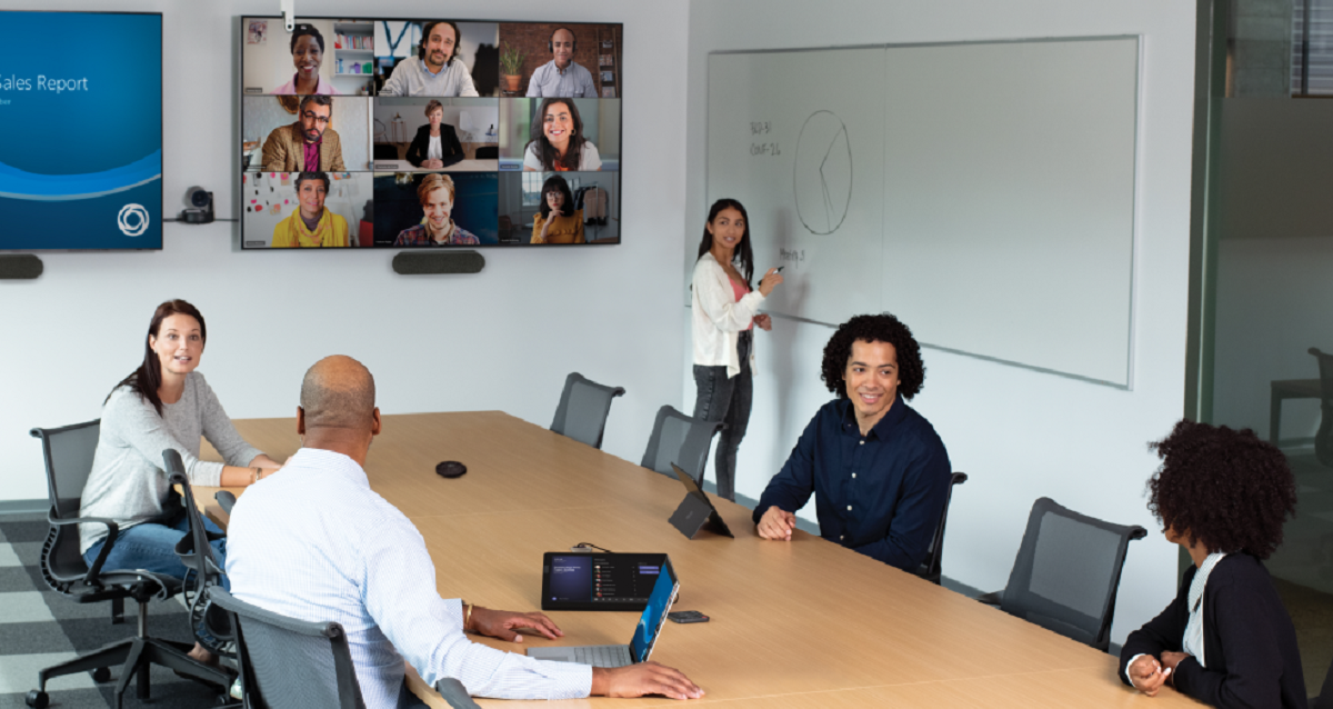 Five people in a conference room holding a video call with nine others.