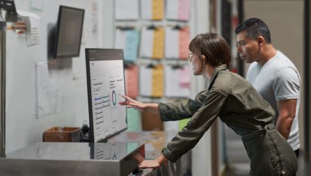a man and a woman reviewing security information on a smart display on the wall in a mail room