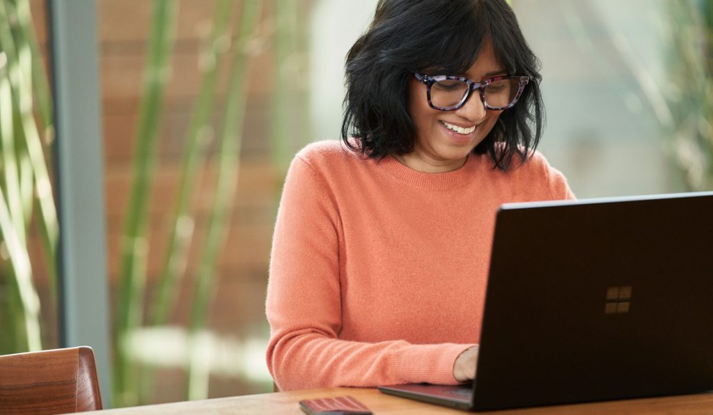 Smiling woman typing on Windows laptop