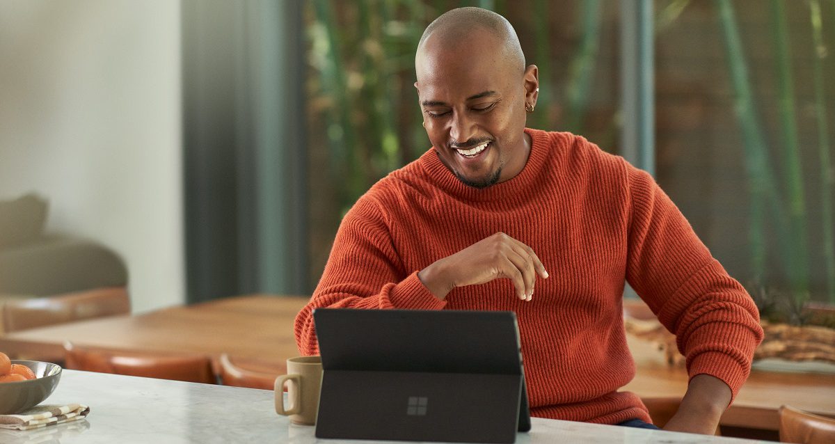 Man at home, smiling at Windows tablet