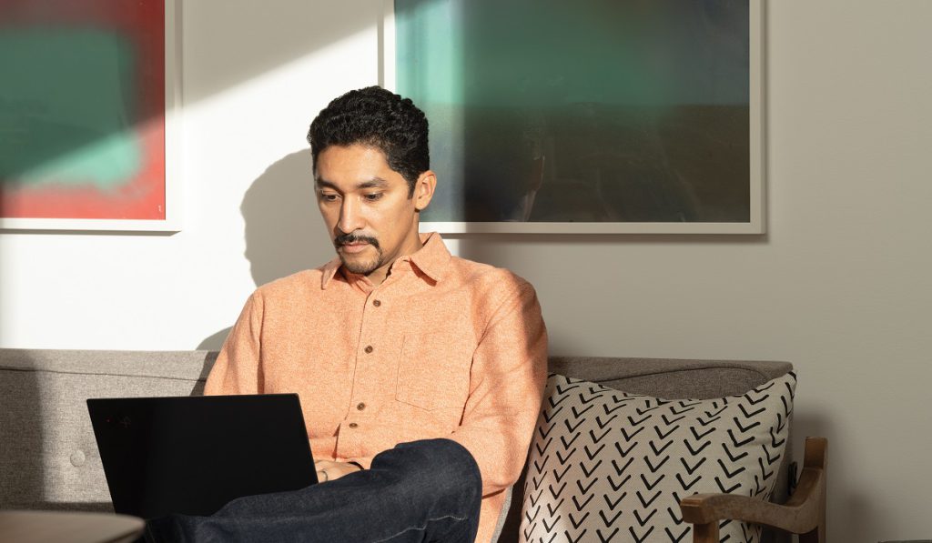 A man sitting on his living room couch working on a laptop
