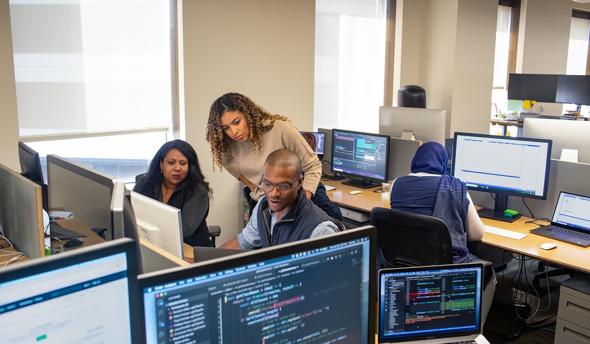 Three coworkers looking at code on a computer in their office