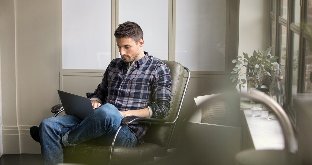 Man works on his laptop in a lounge chair in an office setting